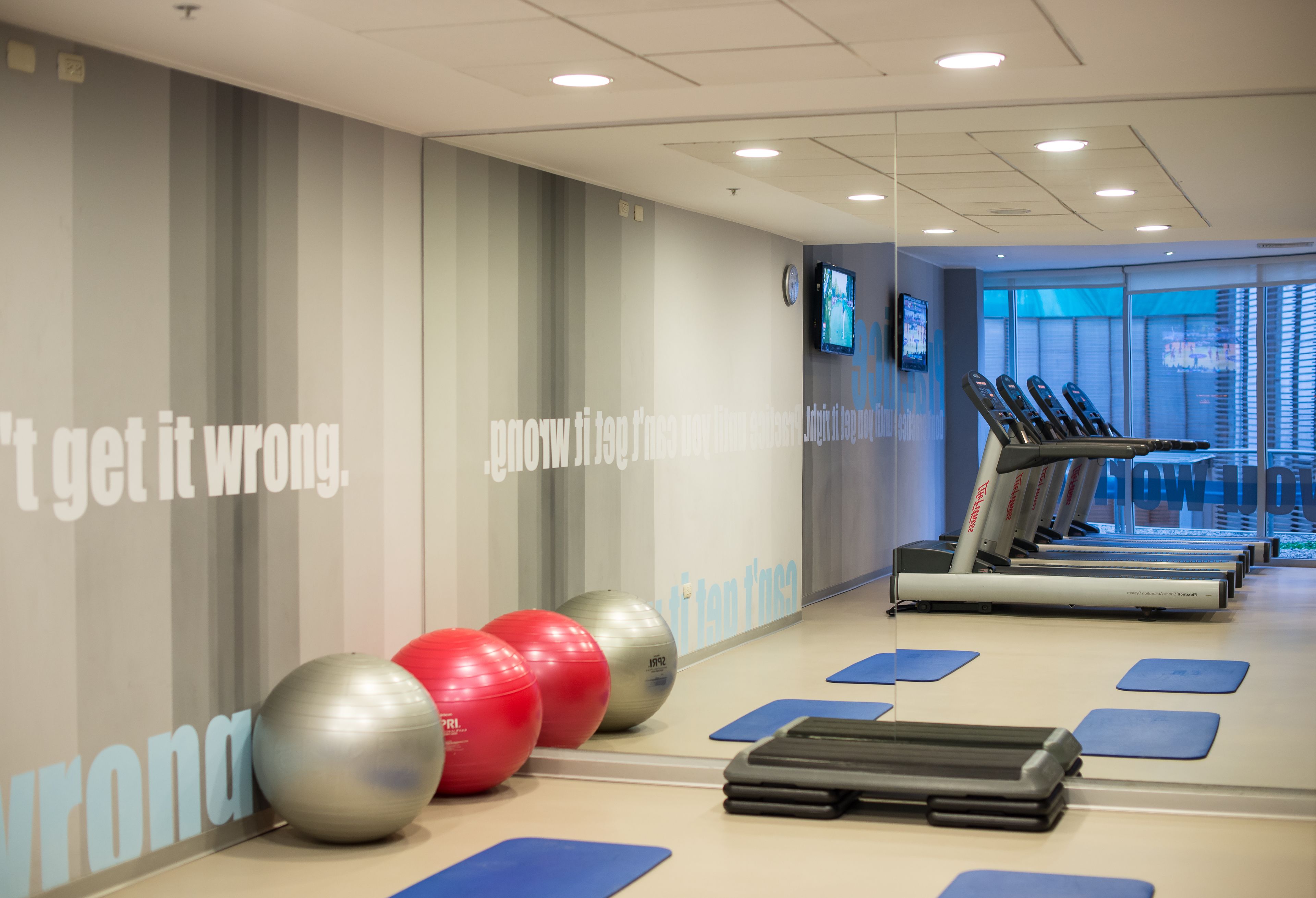 A gym with treadmills, exercise balls, and a motivational wall.