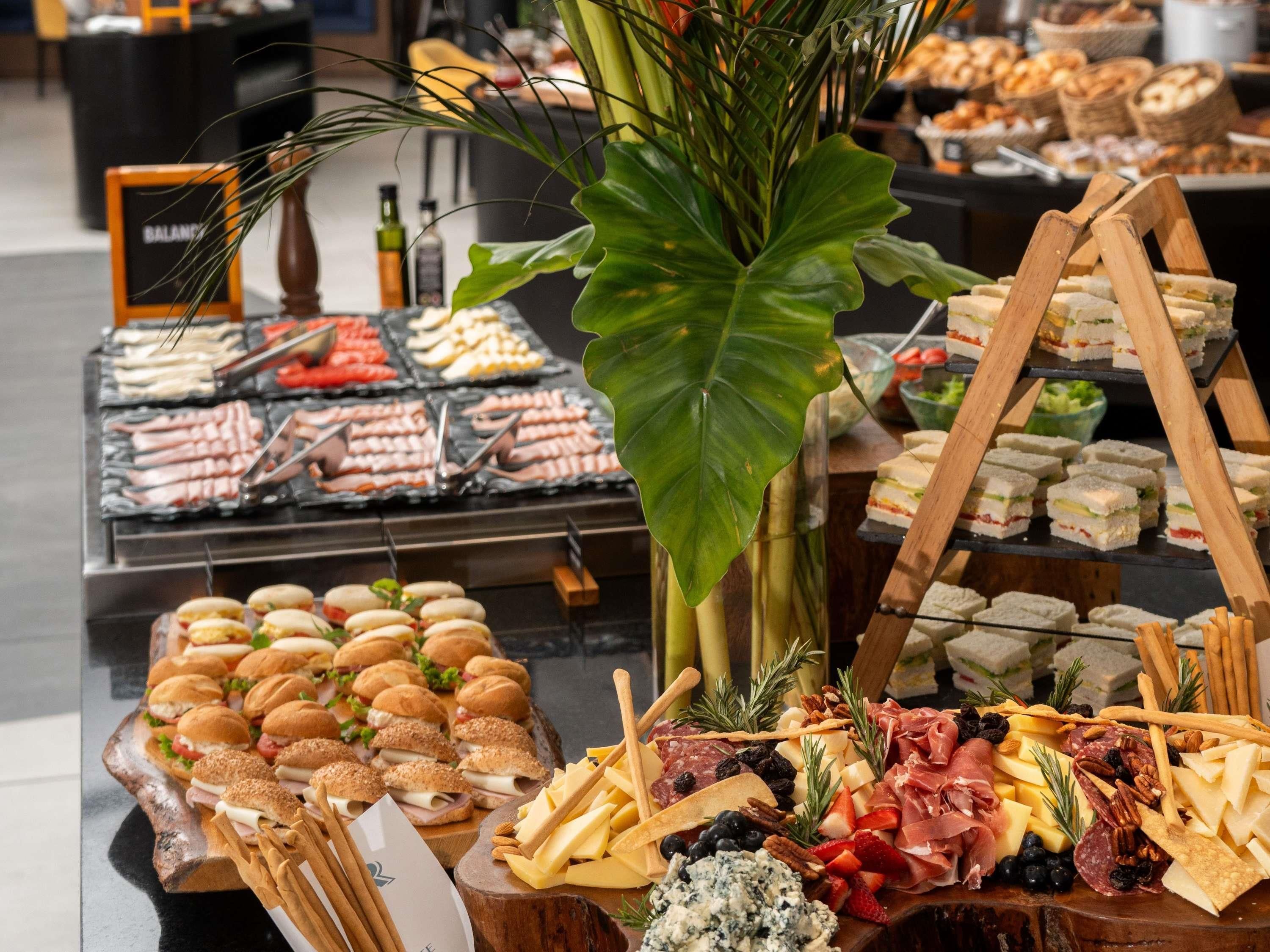 A buffet with various food options including sandwiches, meats, cheeses, and fruits.