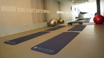 Un estudio de yoga con colchonetas, pelotas de ejercicio y un cartel con mensajes motivacionales.