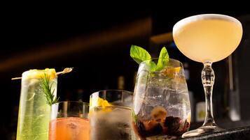 Un bar con diversas bebidas, incluyendo un martini, un cóctel con una rodaja de limón y un vaso con hielo y una ramita de menta.