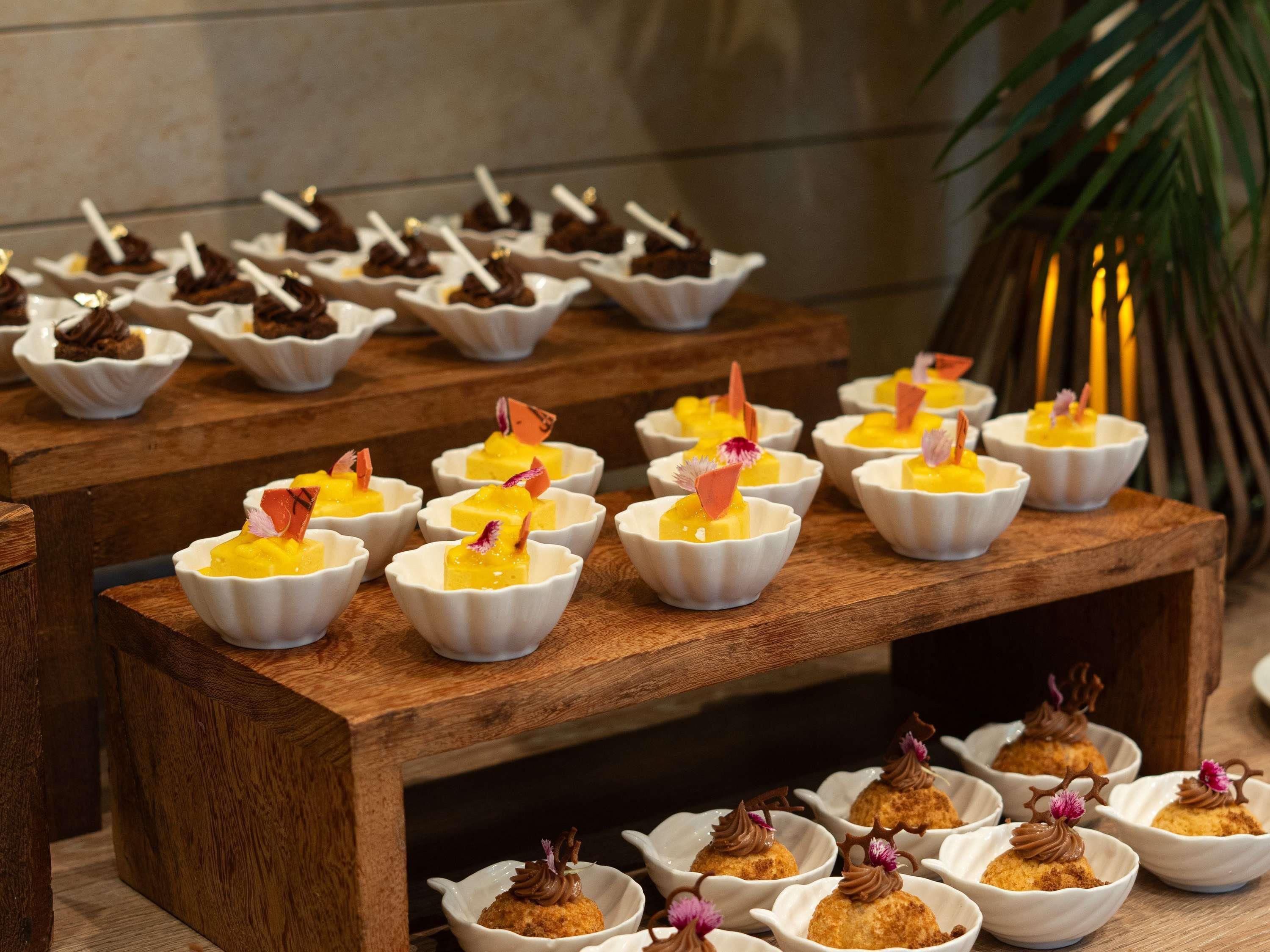A dessert display with various sweet treats in white bowls.