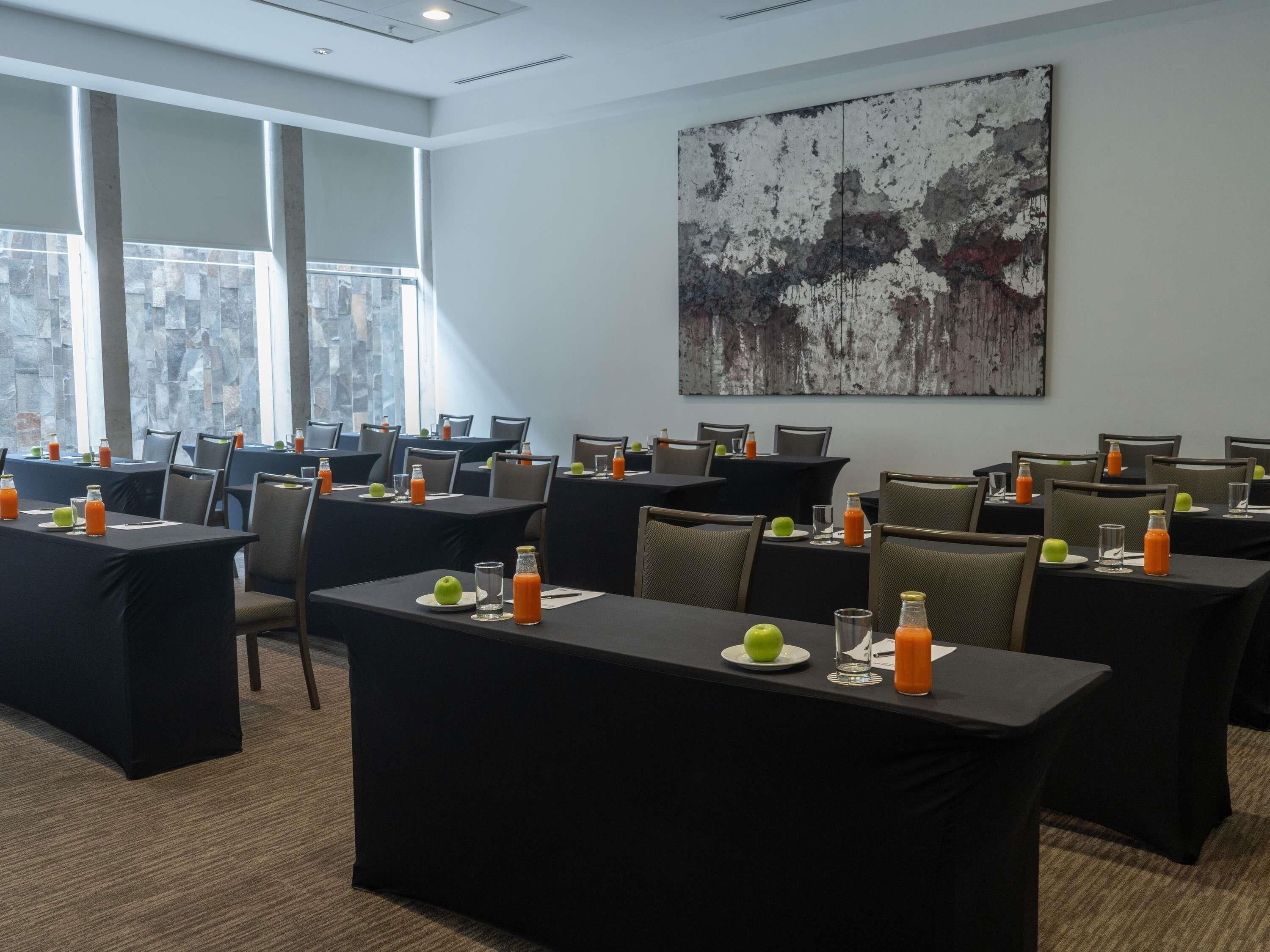 A conference room with tables set for meetings, a large abstract painting on the wall, and a view of the cityscape through large windows.