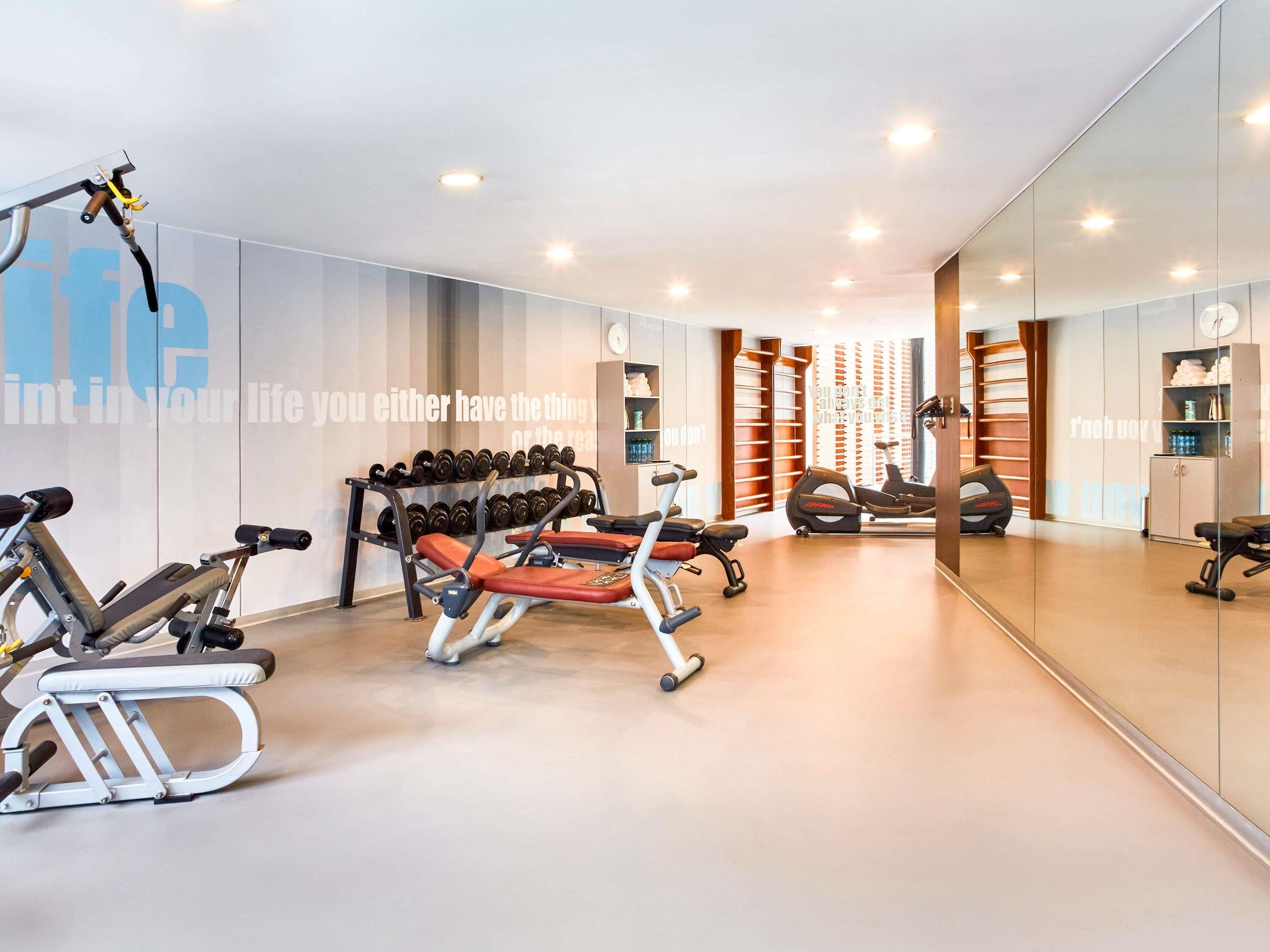 A modern gym with exercise equipment, a mirrored wall, and a motivational quote.