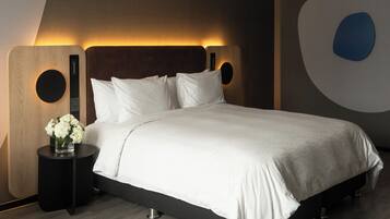 A modern bedroom with a large bed, a nightstand with a vase of flowers, and a unique wall design.