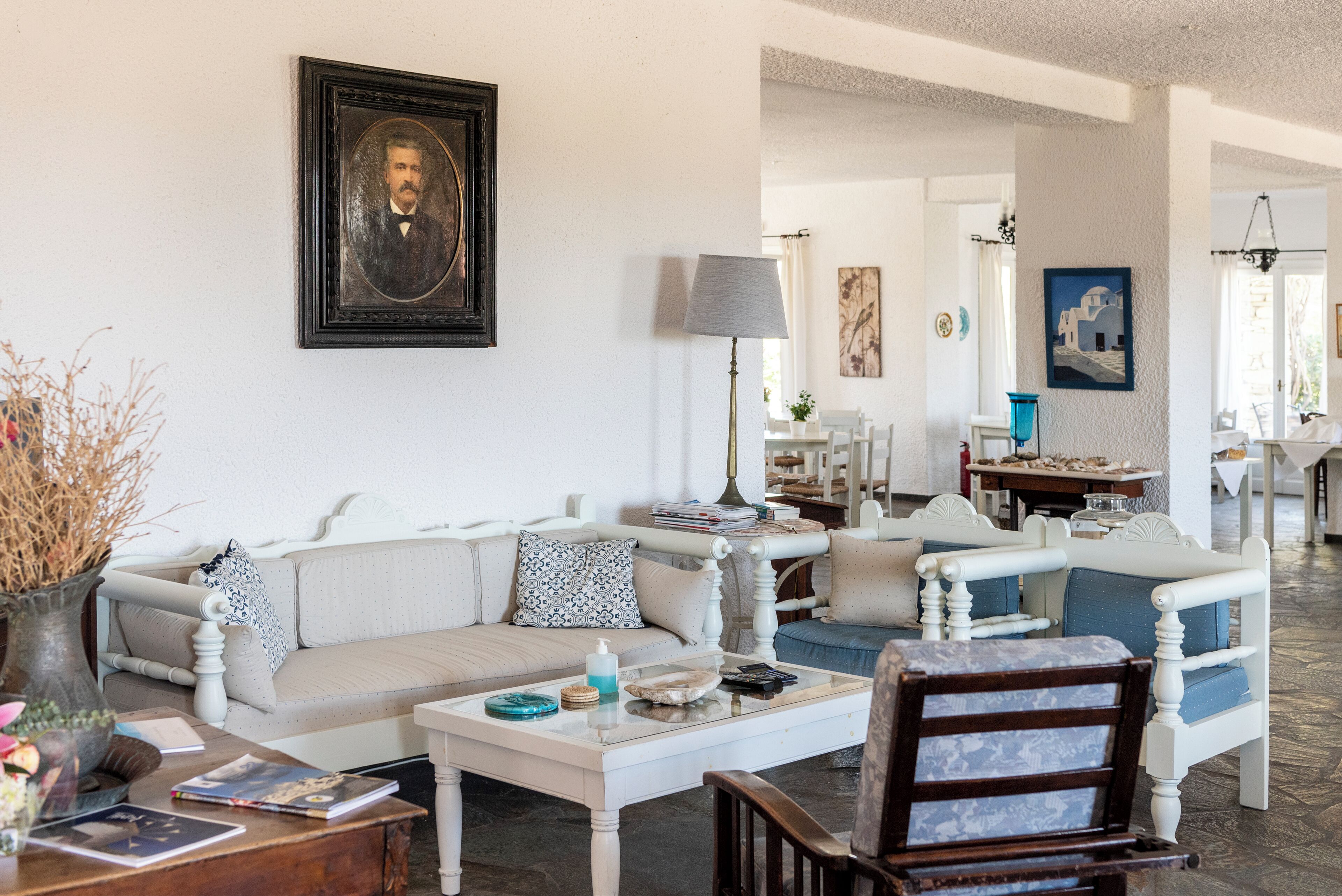 Uma sala de estar com um sofá, cadeiras, uma mesa de centro e um retrato emoldurado na parede.