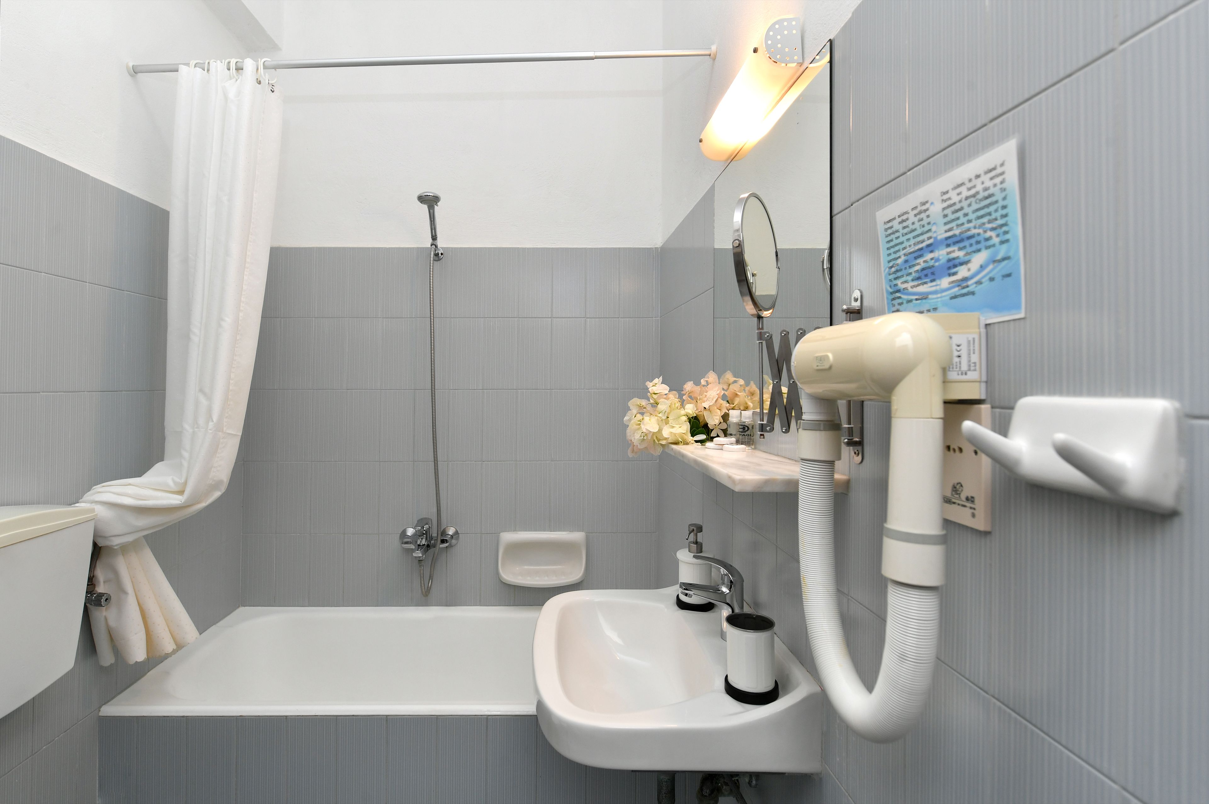 A bathroom with a bathtub, a sink, a shower, and a vanity with a mirror and a light fixture.