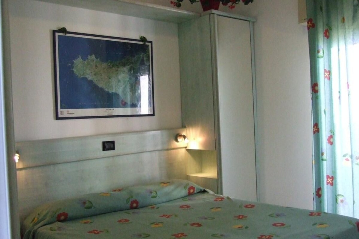 Un dormitorio con cama, un mapa en la pared y un armario.