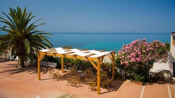 An outdoor patio with a pergola, seating, and a view of the sea. - Costa Makauda Residence (Sciacca)