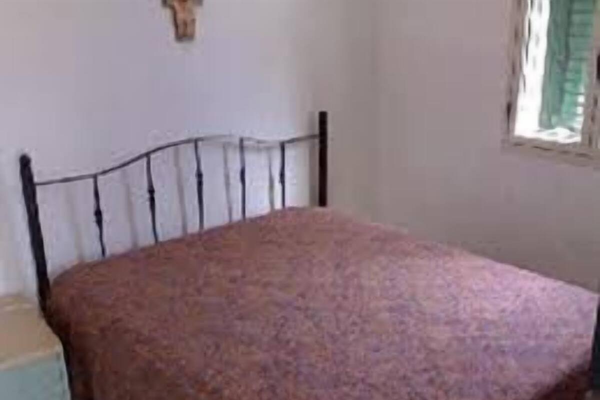 A room with a bed, a small table, and a window with curtains.
