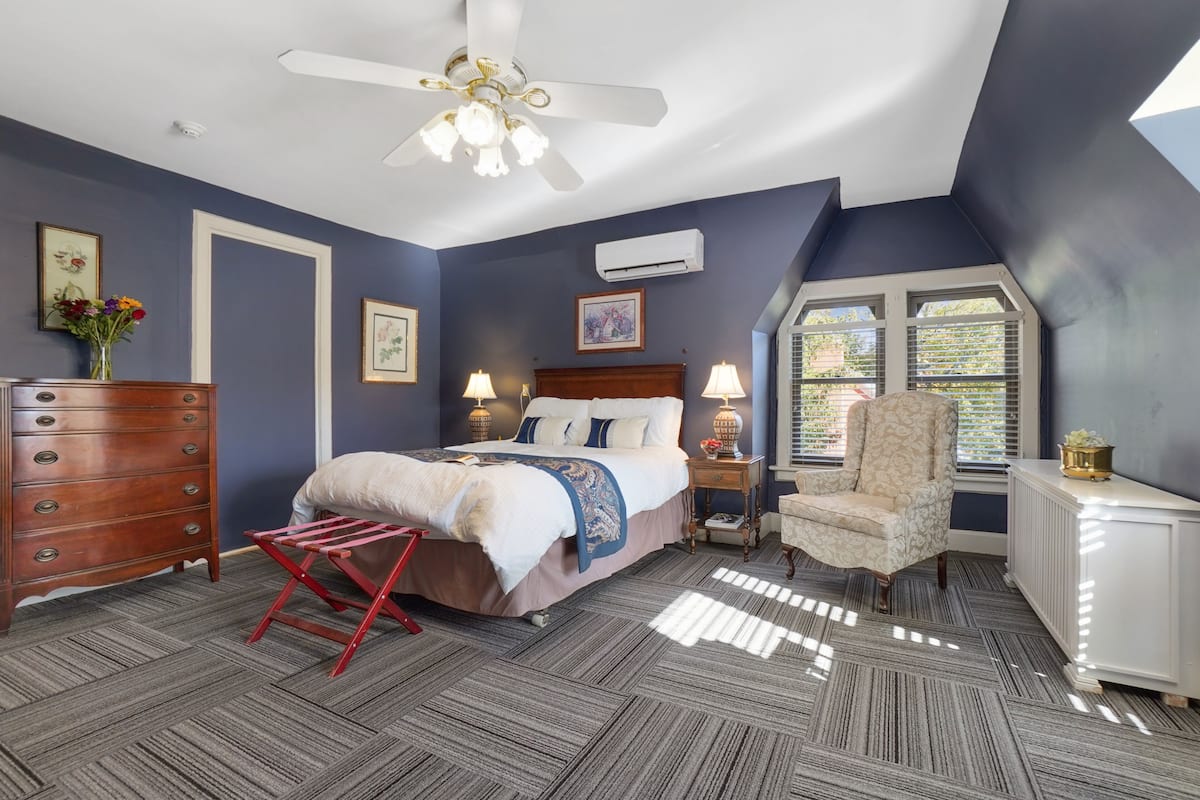 A bedroom with a bed, dresser, chair, and window.