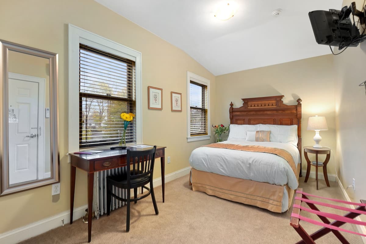 A bedroom with a bed, a desk, and a chair.