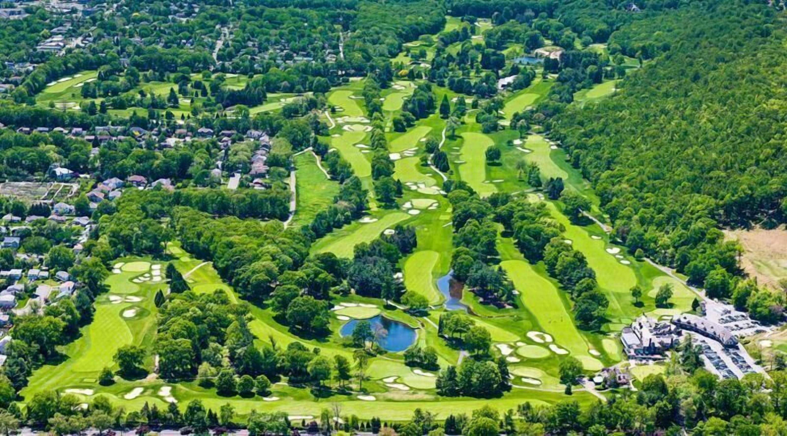An aerial view of a golf course with multiple holes, water hazards, and surrounding residential areas.
