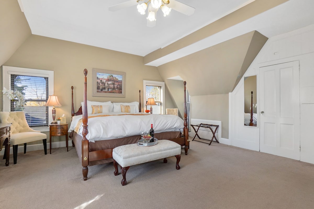 A four-poster bed with a matching bench, a chair, and a bedside table with a lamp.
