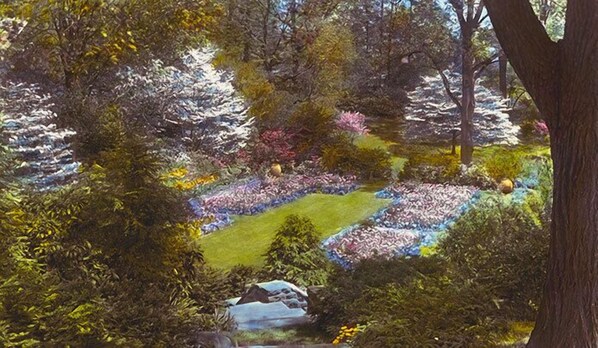 A lush garden with a variety of trees and a small stream.