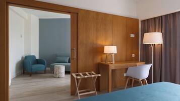 Una habitación de hotel con cama, escritorio con lámpara, silla y una pequeña mesa.