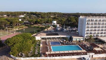 A resort with a swimming pool, sun loungers, and a tennis court.