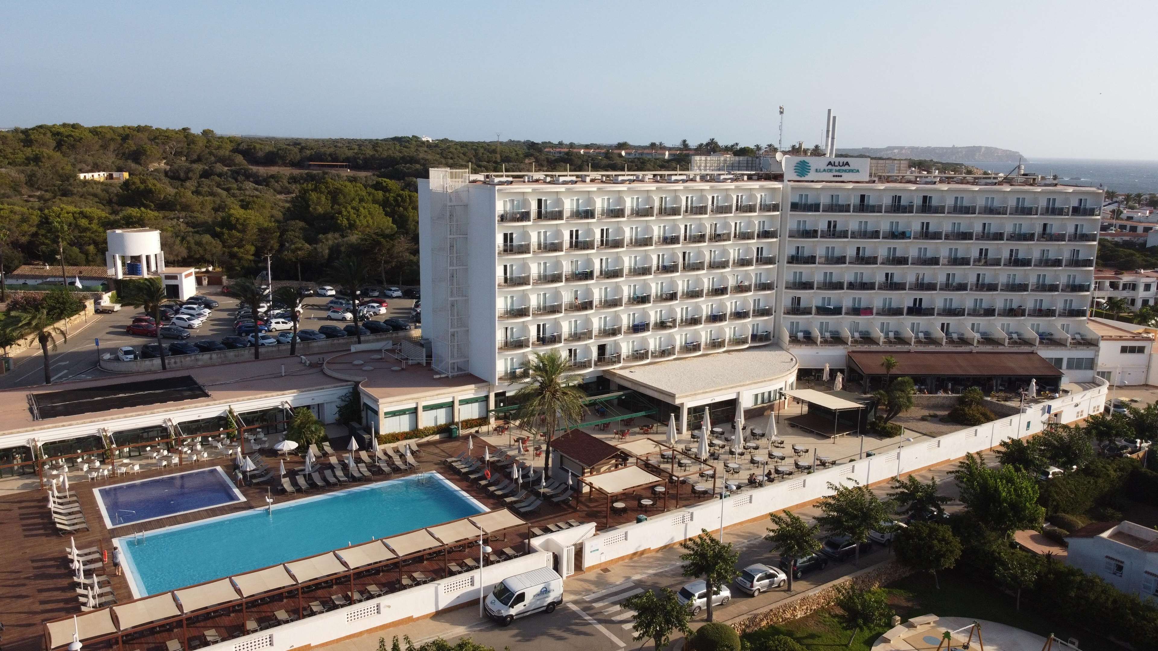 Ein Hotel mit mehreren Etagen, einem Pool und Außenbereichen zum Sitzen.