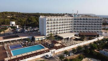 Ein Hotel mit mehreren Etagen, einem Pool und Außenbereichen zum Sitzen.