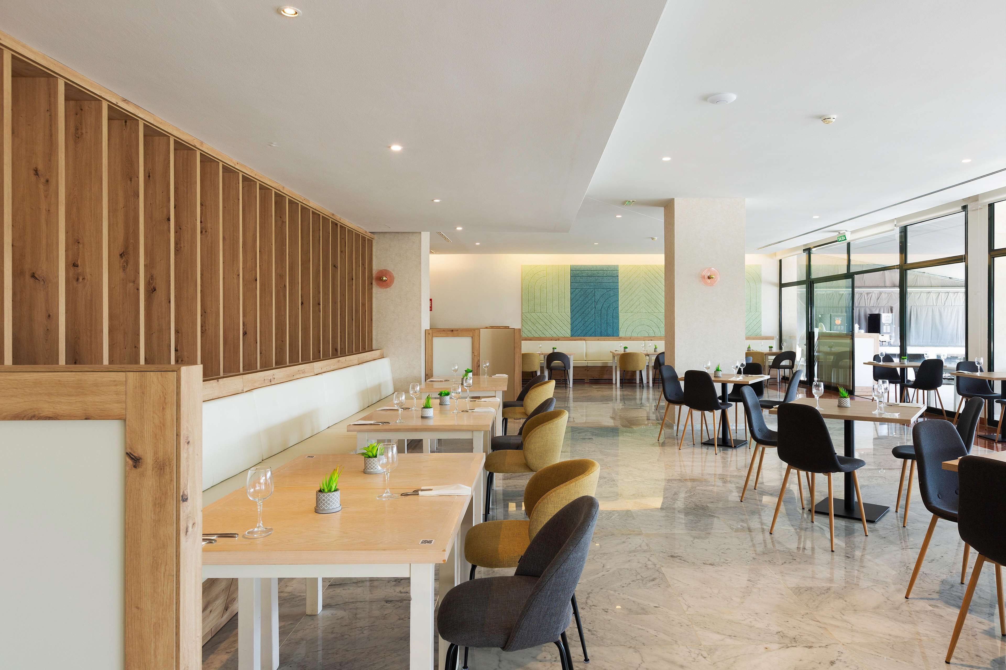A modern dining area with wooden paneling, multiple tables, and chairs.