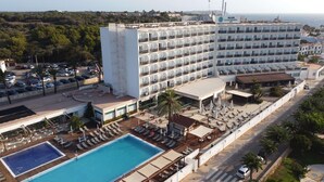 Un hotel con múltiples balcones, piscina y zona de playa.