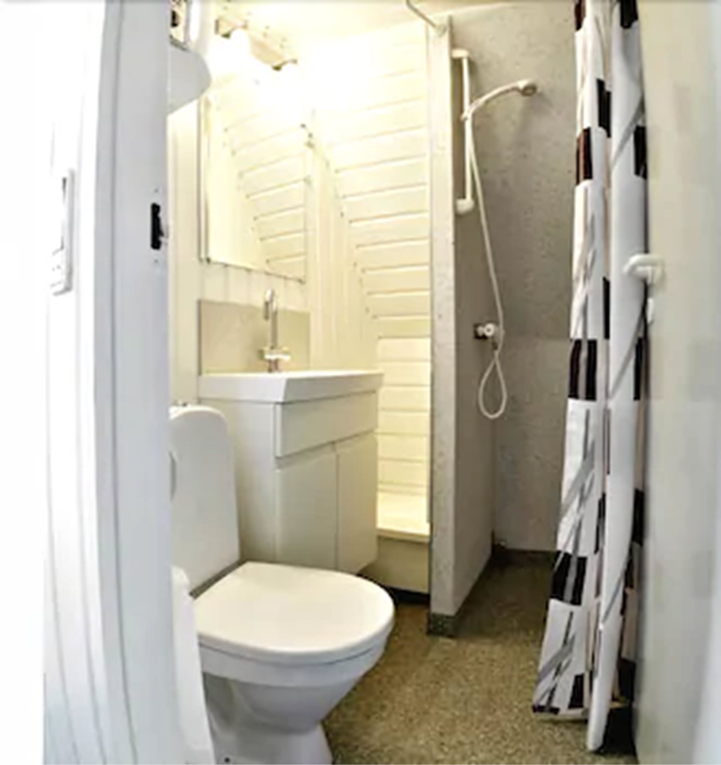 A small bathroom with a toilet, sink, and shower.
