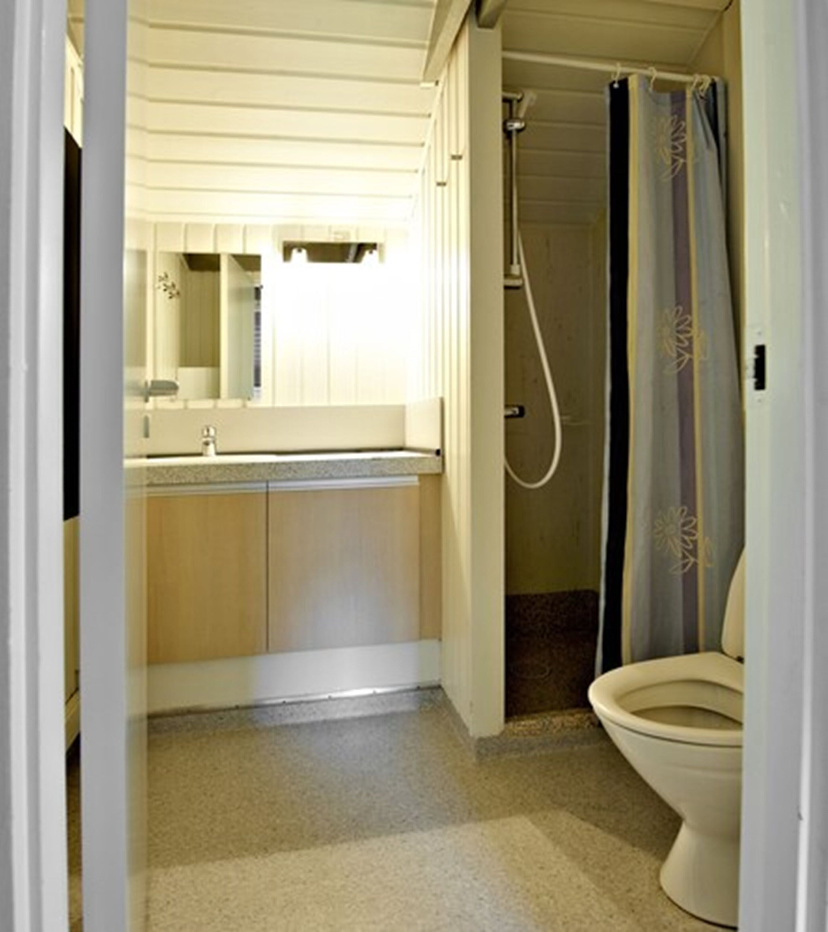 A compact bathroom with a toilet, shower, and sink.