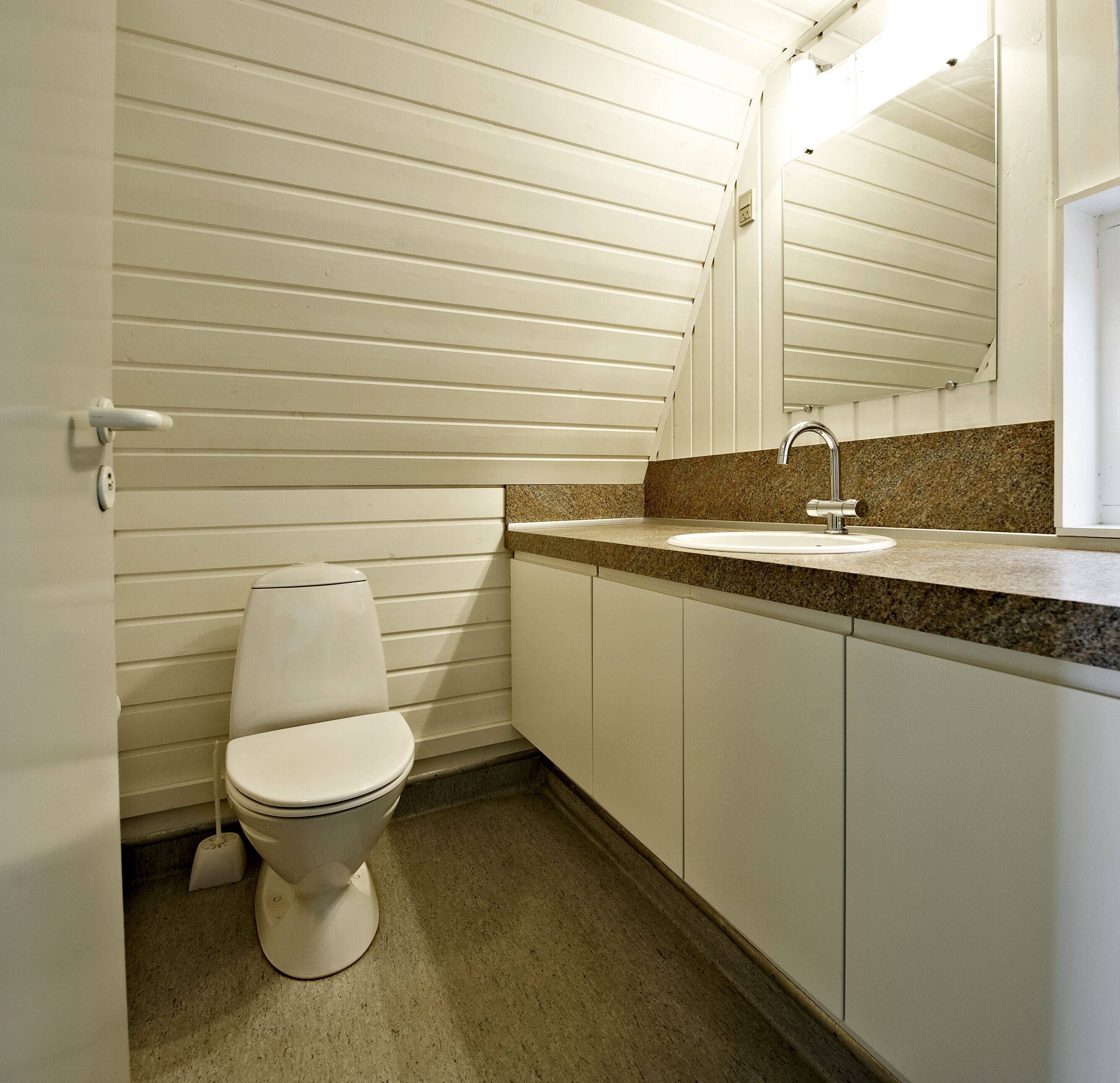 A bathroom with a toilet, sink, and mirror.