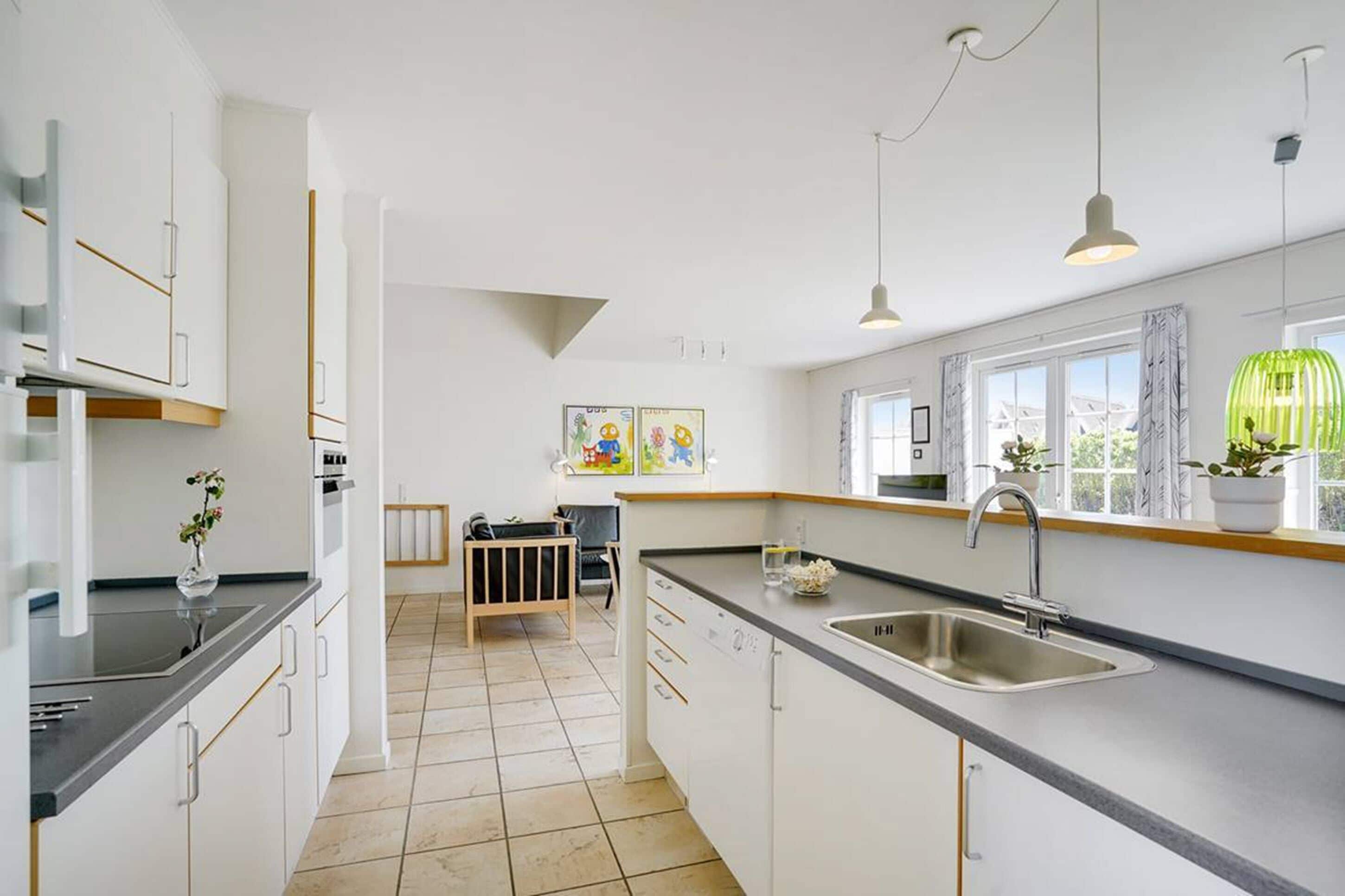 A modern kitchen with white cabinetry, a black countertop, and a large window providing natural light.