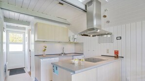Une cuisine moderne dotée d’un îlot central, d’un four encastré et d’une hotte en acier inoxydable.