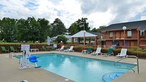 A swimming pool with lounge chairs, a lifeguard stand, and a two-story building with a flag. - Americas Best Value Inn & Suites Sheridan (Sheridan)