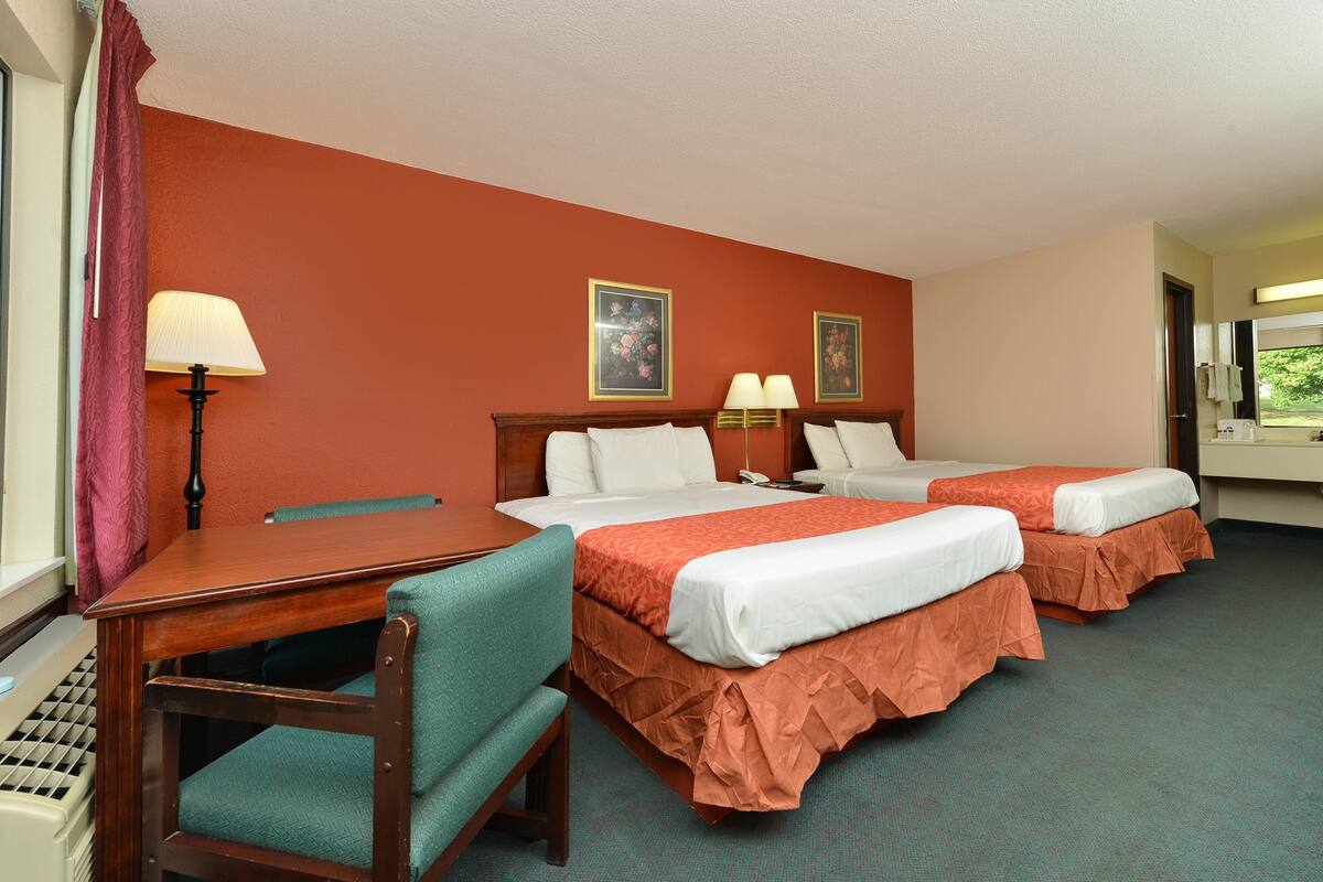 Habitación de hotel con dos camas, un escritorio y una silla.
