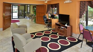A hotel room with a TV, a desk, a computer, and a dining area with chairs. - Americas Best Value Inn & Suites Sheridan (Sheridan)