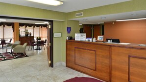 A hotel lobby with a reception desk, a dining area with chairs and a table, and a sign indicating breakfast availability. - Americas Best Value Inn & Suites Sheridan (Sheridan)