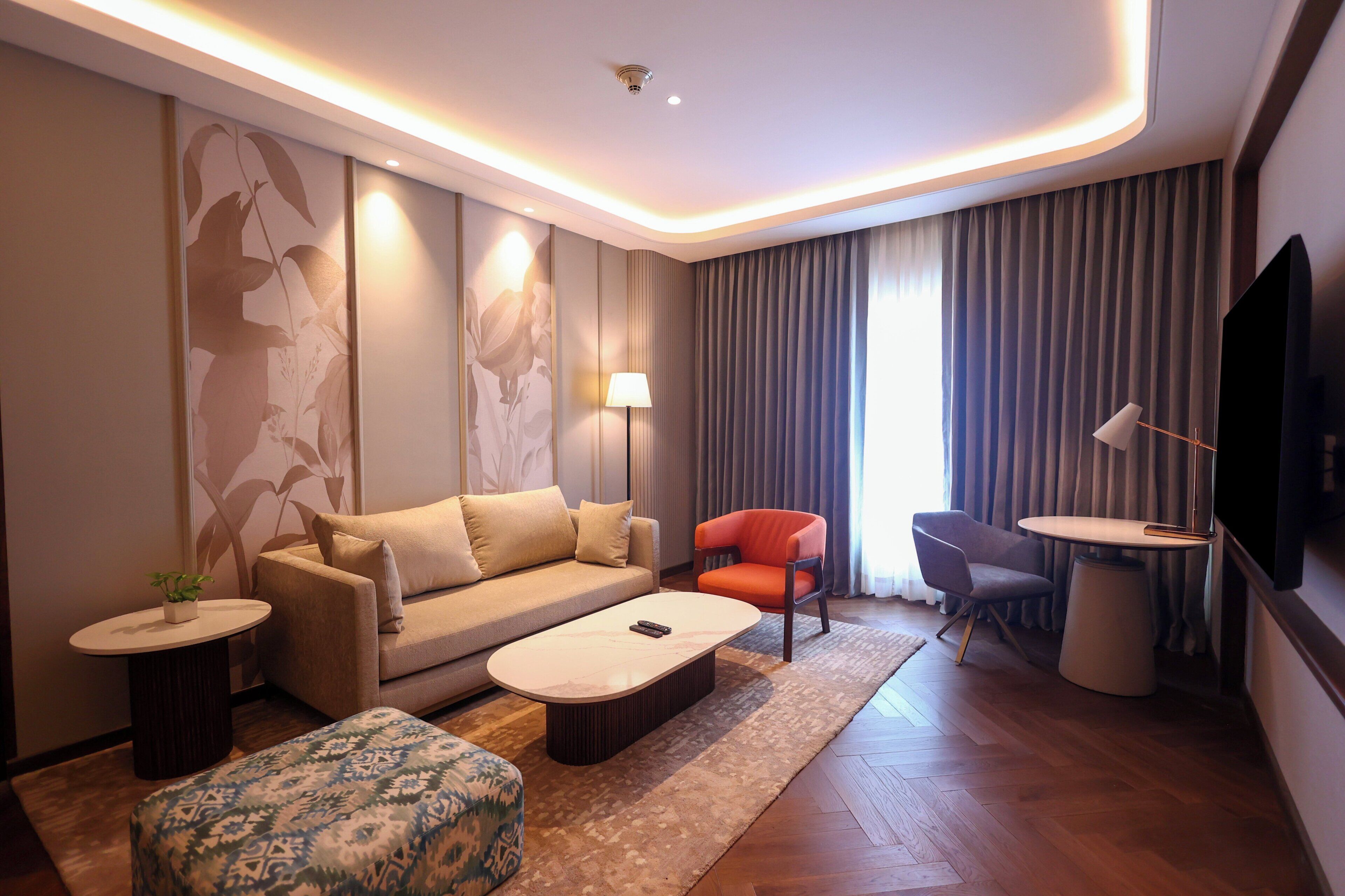 A modern living room with a sofa, ottoman, coffee table, and a TV.