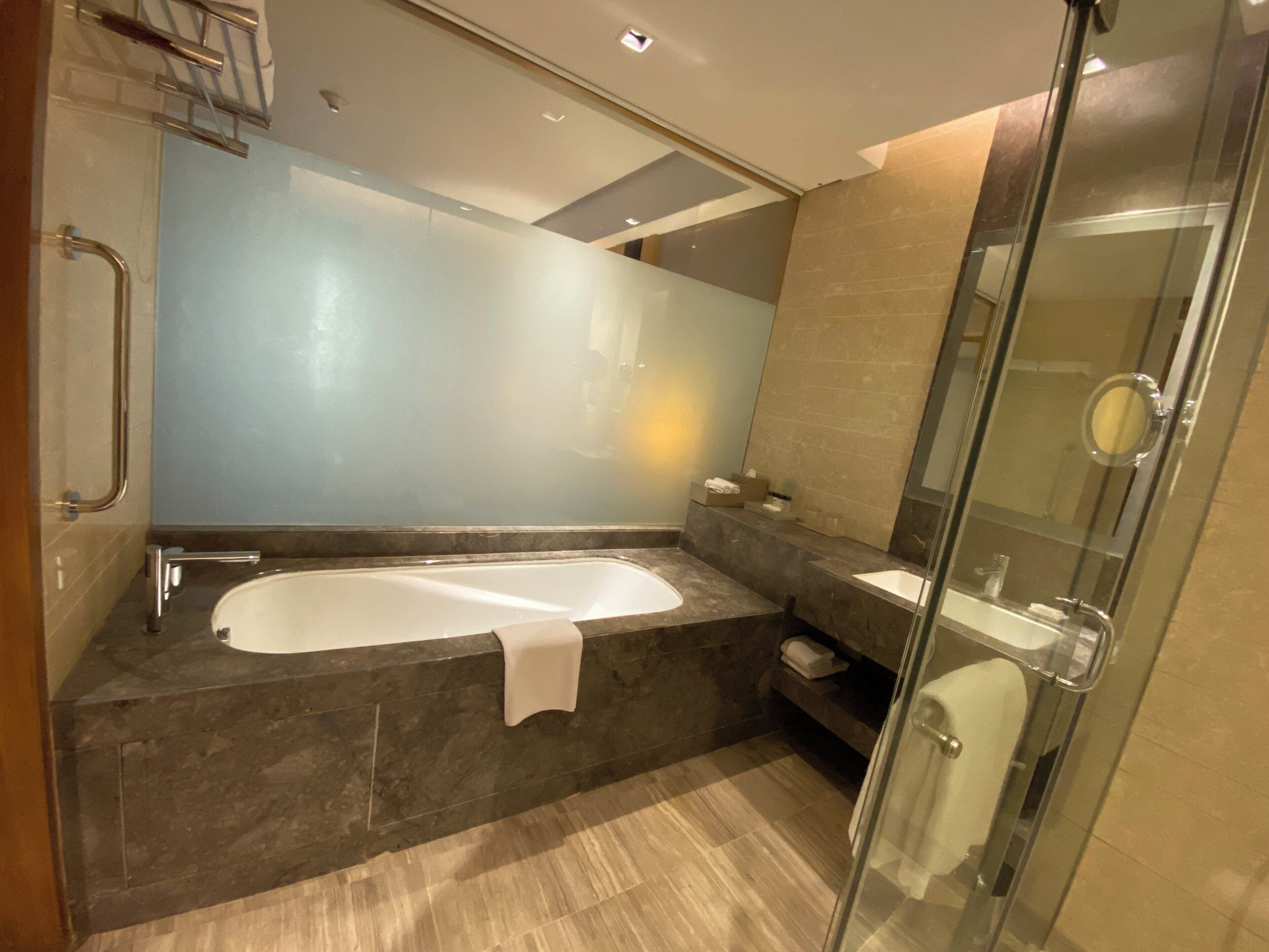 A modern bathroom with a large bathtub, a glass shower enclosure, and a marble countertop.