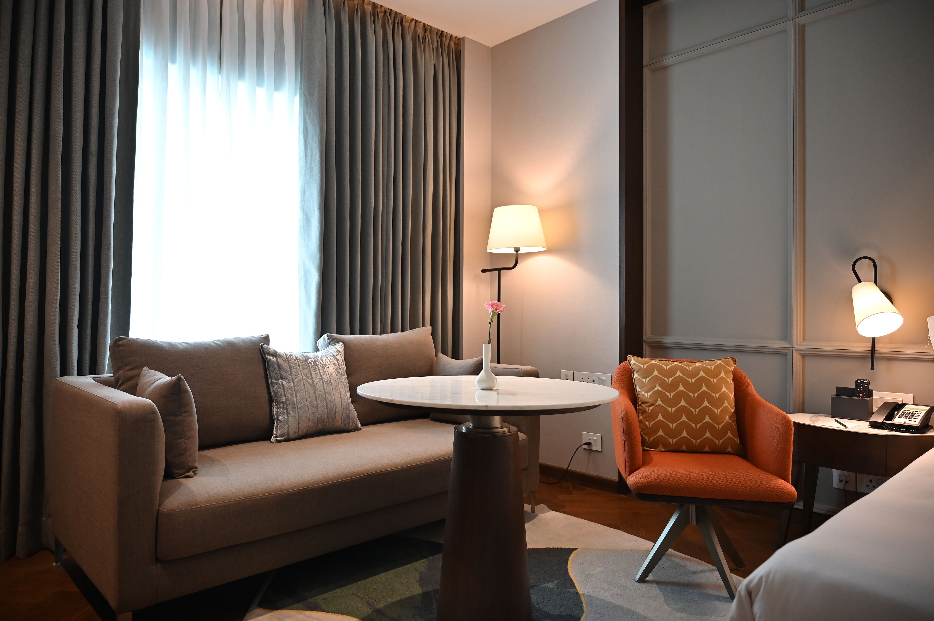 Une chambre d’hôtel avec un canapé, une petite table, une chaise, une lampe et un lit.