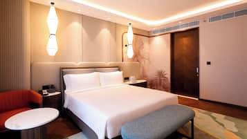 Une chambre d’hôtel avec un grand lit, une table de chevet, une chaise, une petite table, un banc et une armoire.