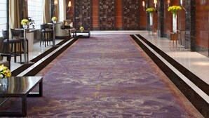 Un'ampia hall con un grande lampadario, una moquette decorata e una reception con sedie.