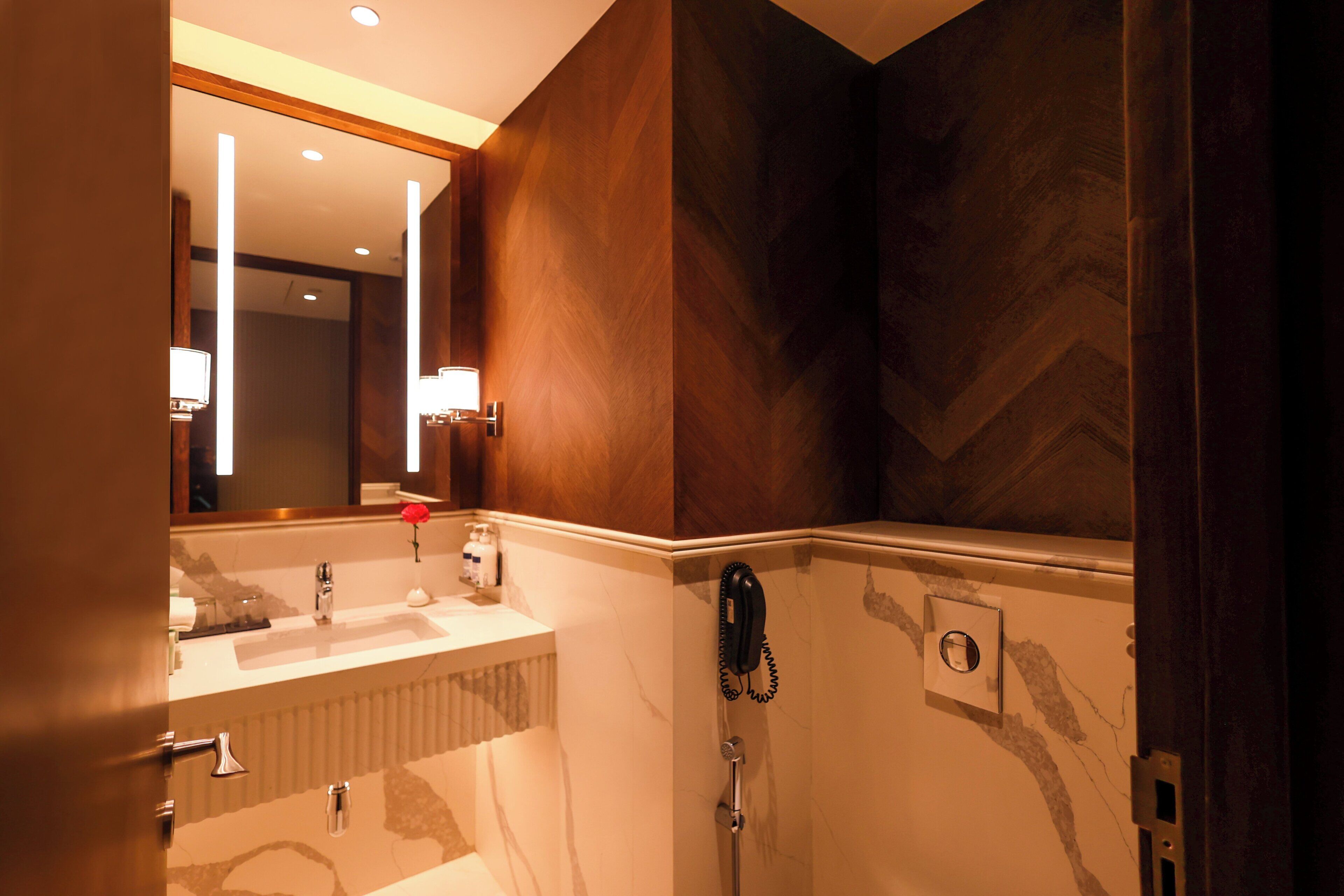 A bathroom with a vanity, mirror, and a telephone.