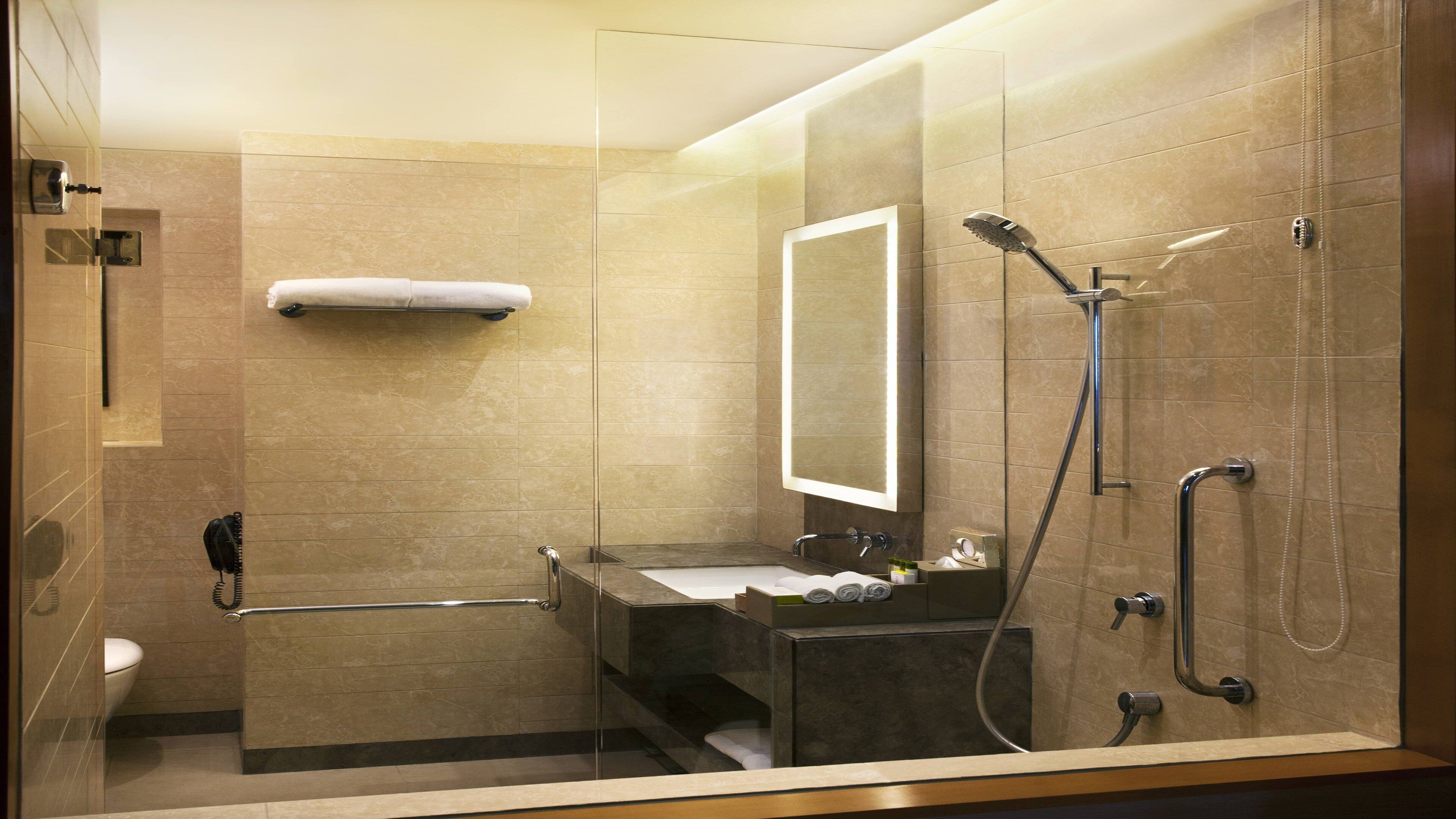 A modern bathroom with a glass-enclosed shower, a vanity with a sink, and a towel rack.