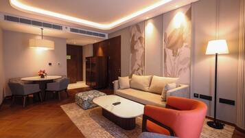 A modern hotel room with a round dining table, a sofa, a coffee table, and a floor lamp.