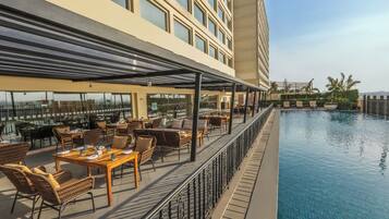 A rooftop pool area with outdoor seating and a view of the city.