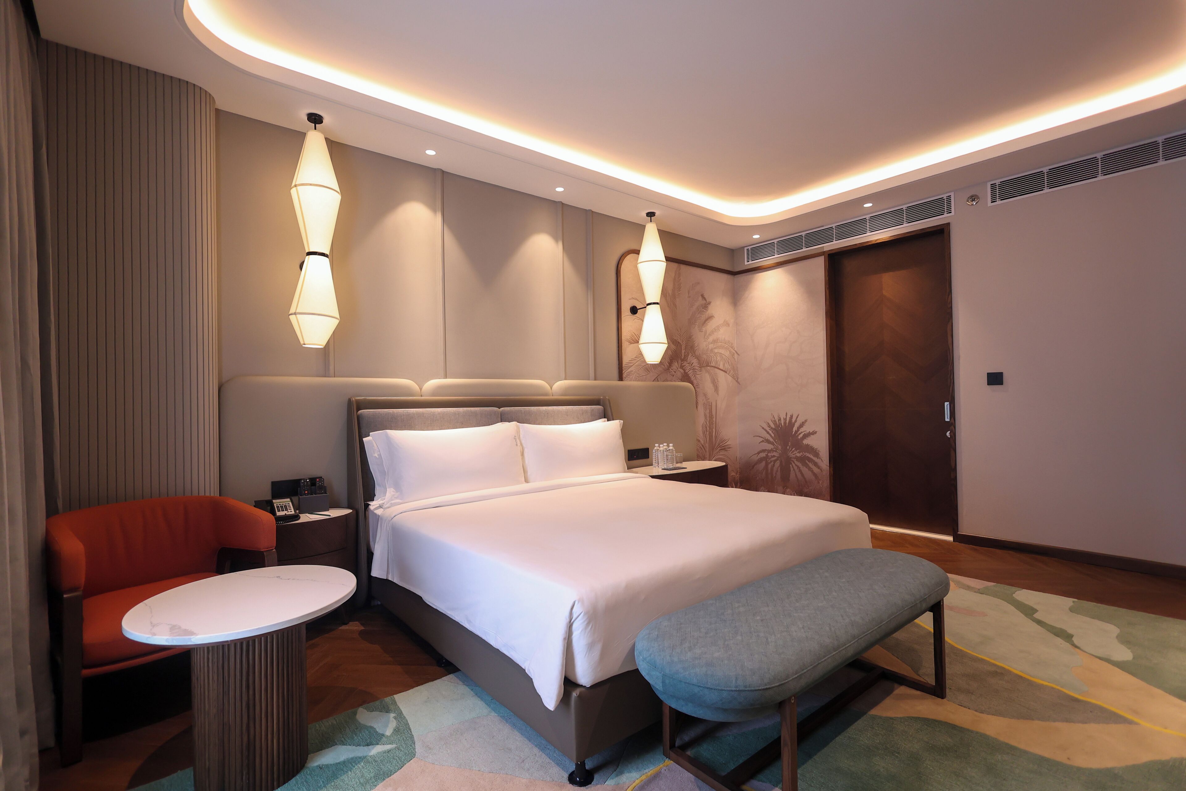 A modern hotel room with a large bed, bedside tables, a seating area, and ambient lighting.
