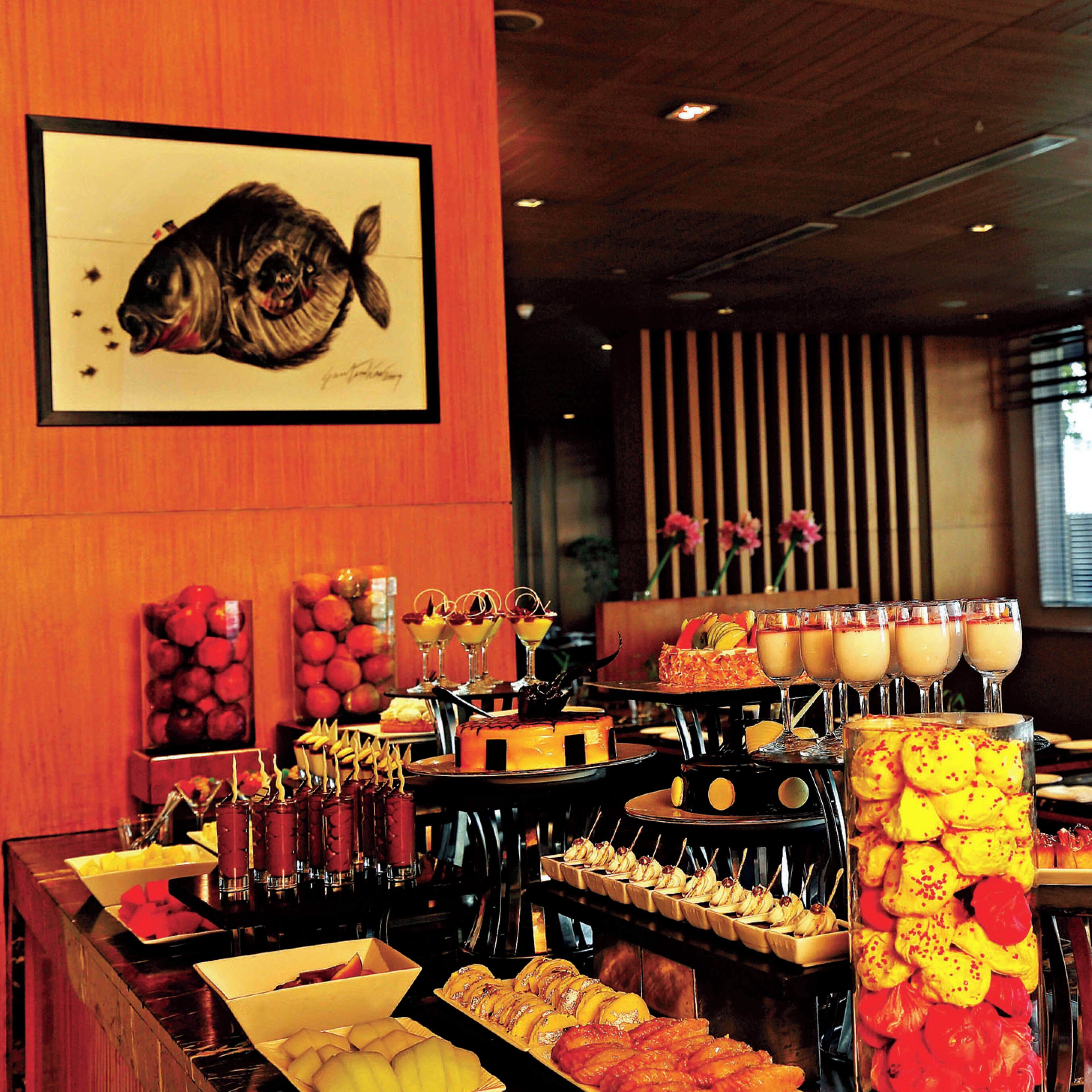 A buffet with various food items and a framed fish artwork on the wall.