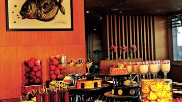 A buffet with various food items and a framed fish artwork on the wall.