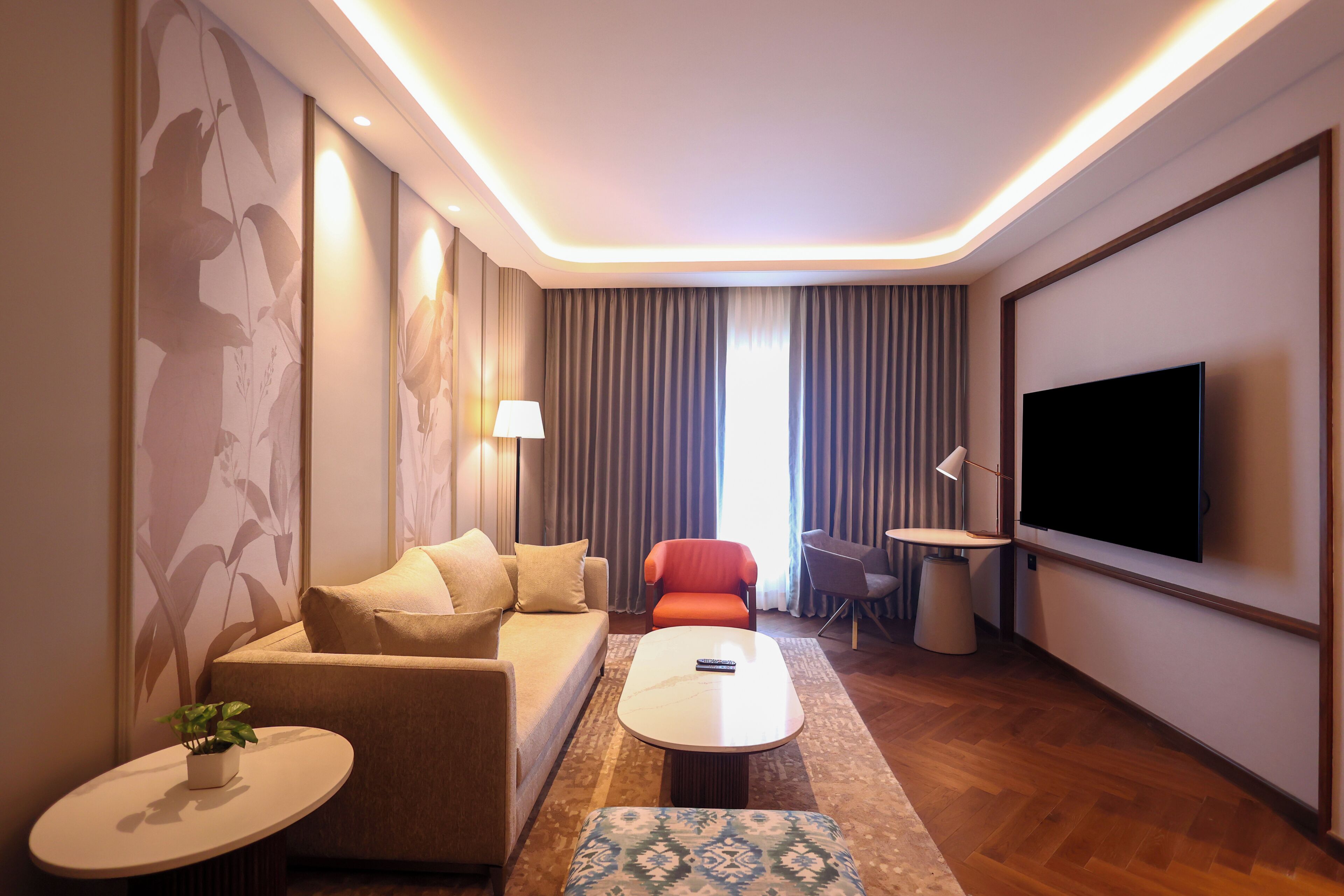 Habitación de hotel moderna con sofá, sillón, mesa de centro y televisión.
