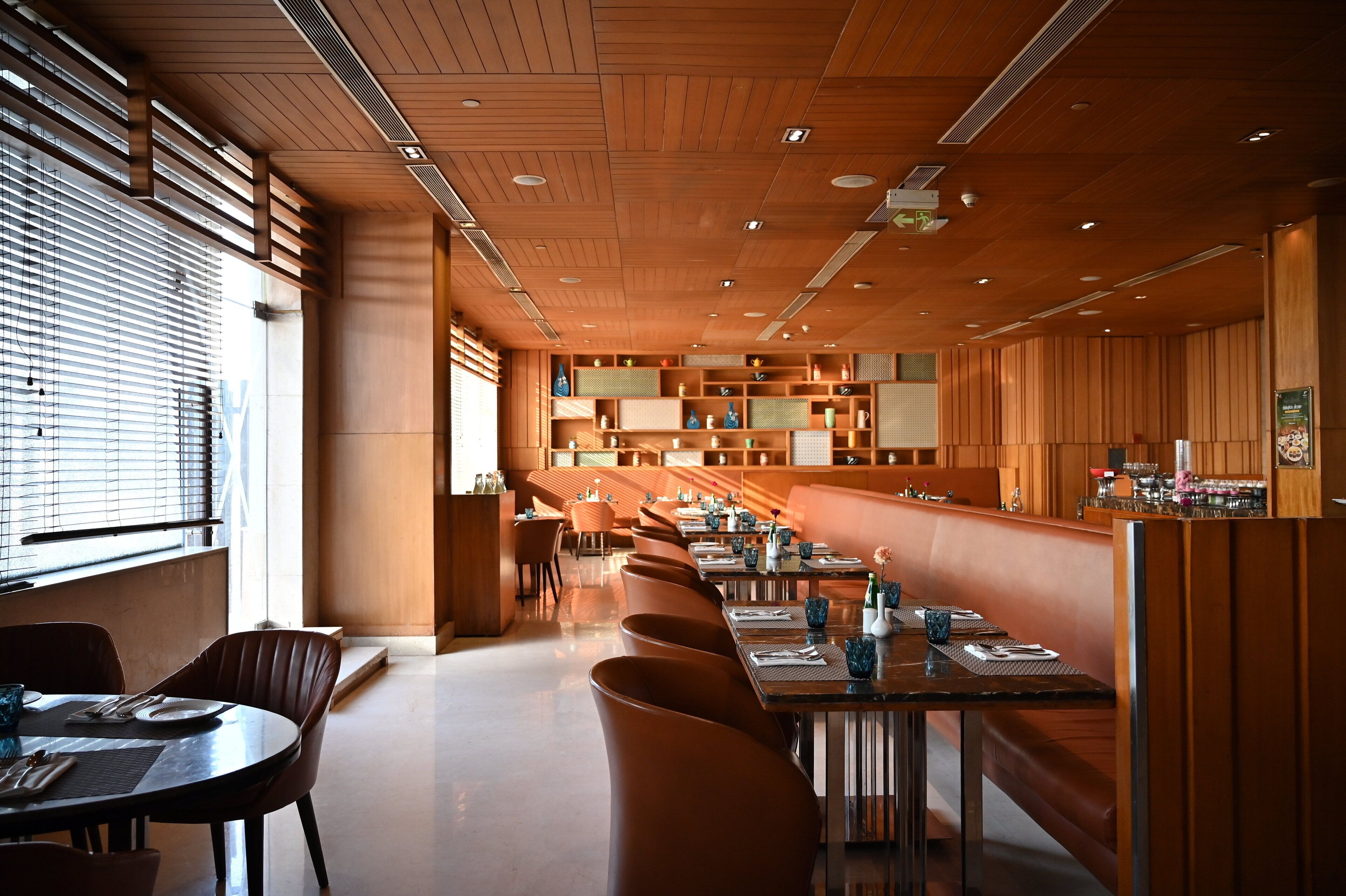 Een modern restaurant met houten lambrisering, lange gedeelde tafels en een bar.