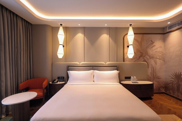 A hotel room with a large bed, two bedside tables, a chair, and a small table.