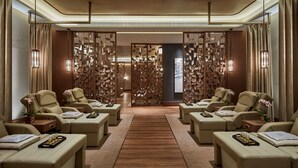 A spa room with multiple massage chairs, a wooden floor, and a decorative partition with hanging lights. - Galaxy Hotel (Cotai)