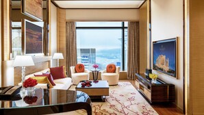 A modern hotel room with a large window, a sofa set, a coffee table, and a TV. - Galaxy Hotel (Cotai)